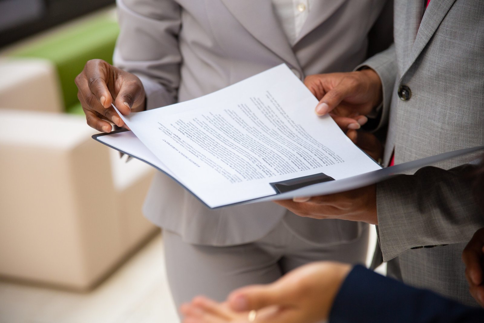 Diverse business partners reading contract together. Business man and woman wearing formal suits, standing and holding open folder with document. Agreement concept
